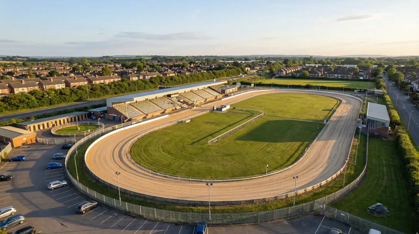 Aerial view of a UK greyhound racing stadium showing the oval sand track and spectator stands